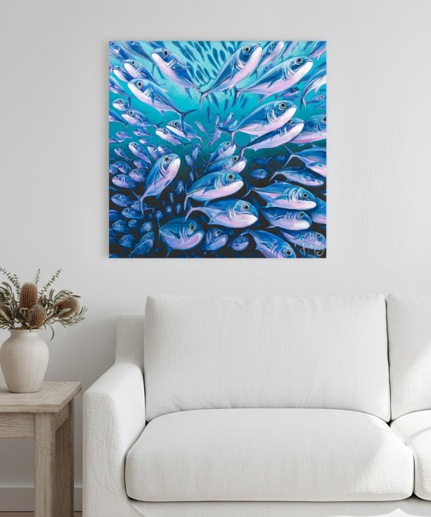 Framed artwork of fishl on a wall above a white sofa.