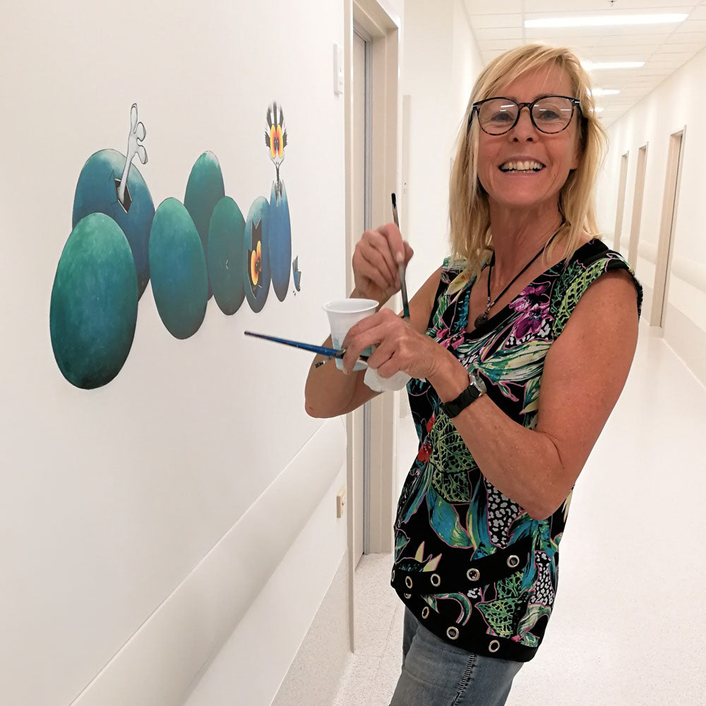 Wendy Binks painting a Stripey emu mural in the corridor of the children's ward at Fiona Stanley Hospital, Perth, Western Australia